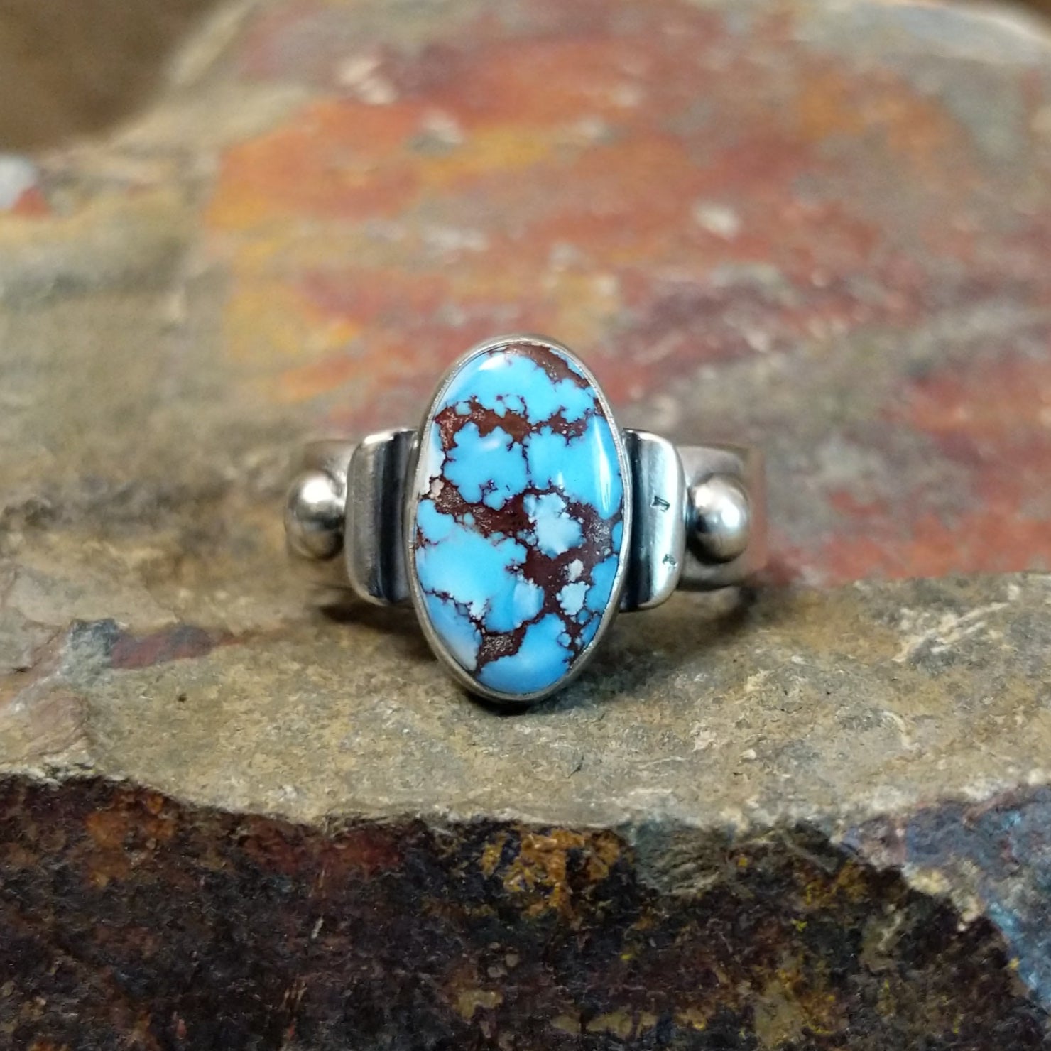 Golden Hills turquoise stone with prominent matrix veining sits in a smooth silver bezel, accented by silver ball details.