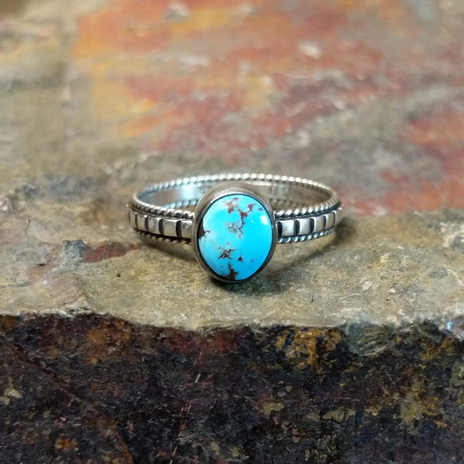 Silver ring with a round Golden Hills turquoise stone in a smooth bezel, framed by a twisted, ribbed silver band.
