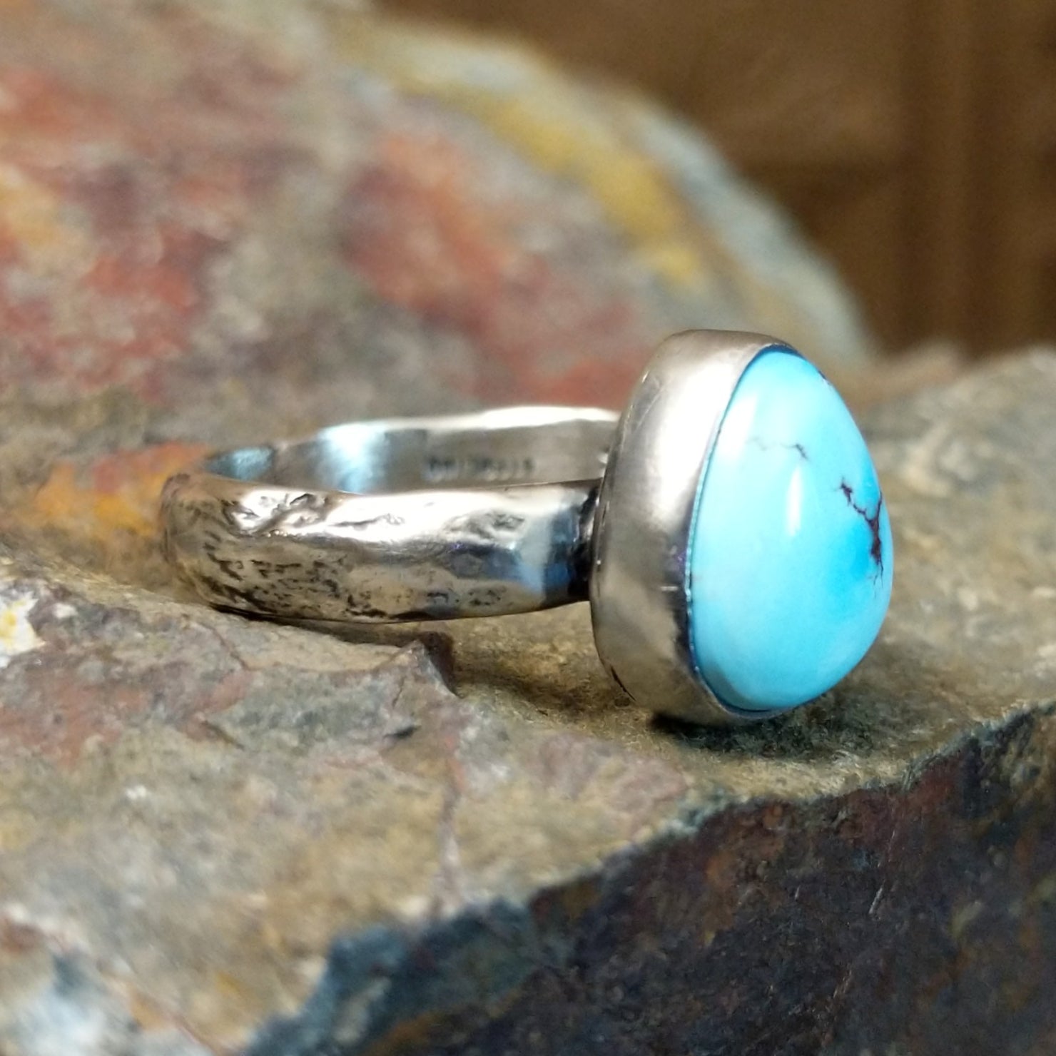 Triangular turquoise bezel set on a textured silver band.