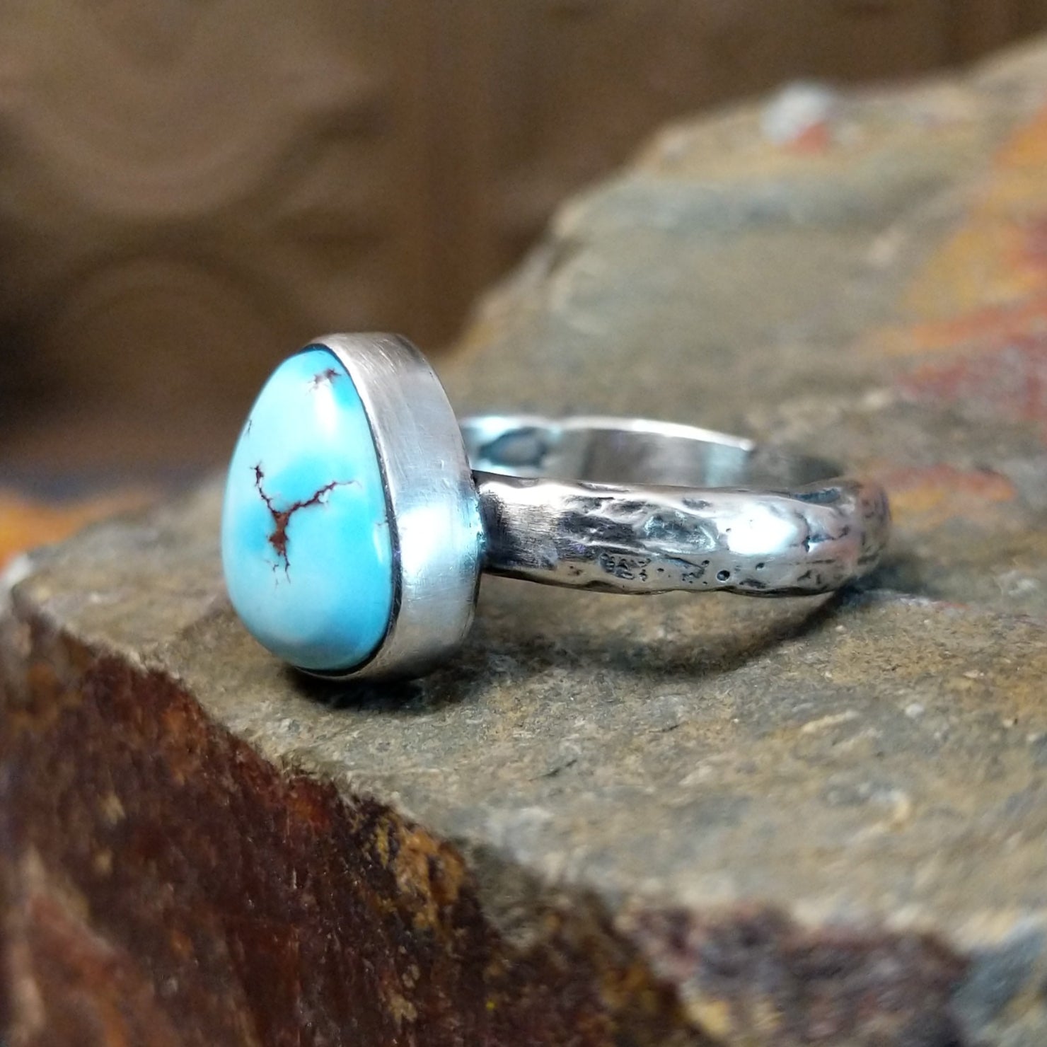 Triangular turquoise bezel set on a textured silver band.