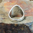 The ring’s polished silver back shows a subtle signature stamp.