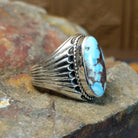 The ring’s band features ribbed silver detailing, complementing the turquoise’s earthy tones.