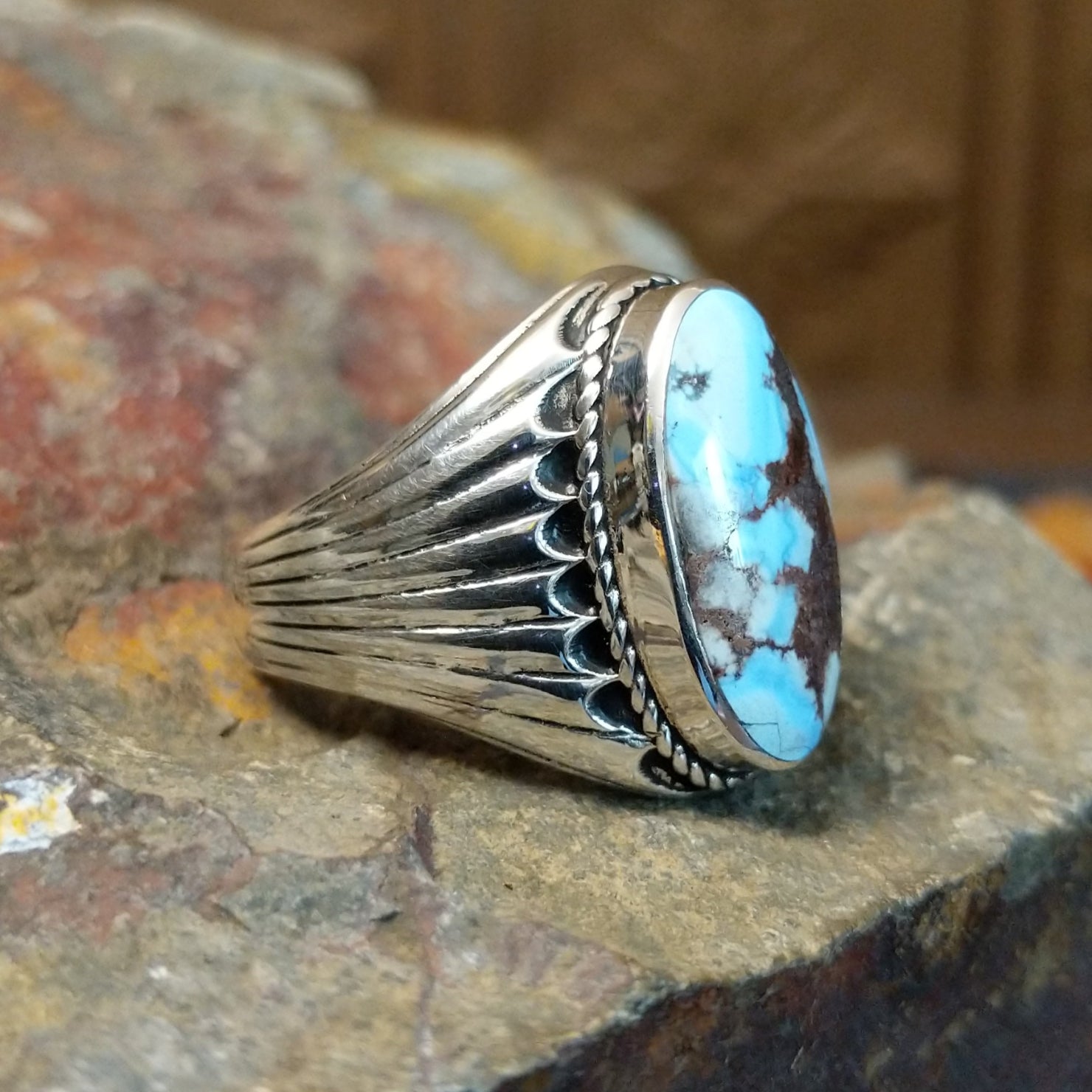 The ring’s band features ribbed silver detailing, complementing the turquoise’s earthy tones.