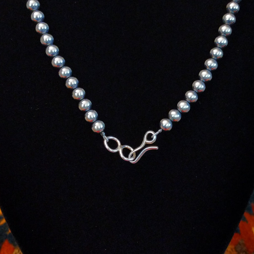 The small clasp on the chain of the beaded necklace.