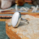 Sterling silver ring by Sheryl Martinez featuring an elongated oval White Buffalo stone with subtle dark veining and an elegant split-shank band; side view.