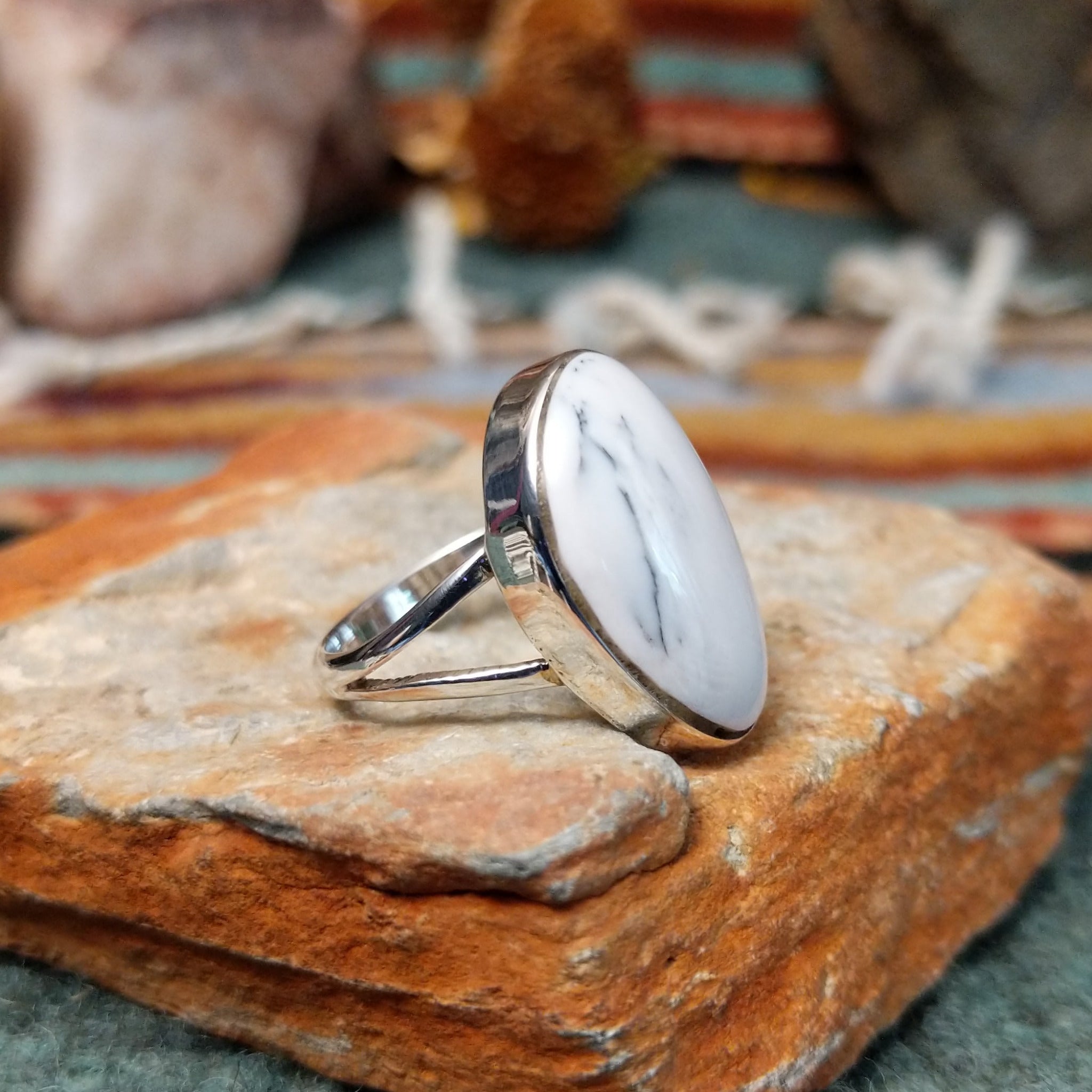 Sterling silver ring by Sheryl Martinez featuring an elongated oval White Buffalo stone with subtle dark veining and an elegant split-shank band; side view.
