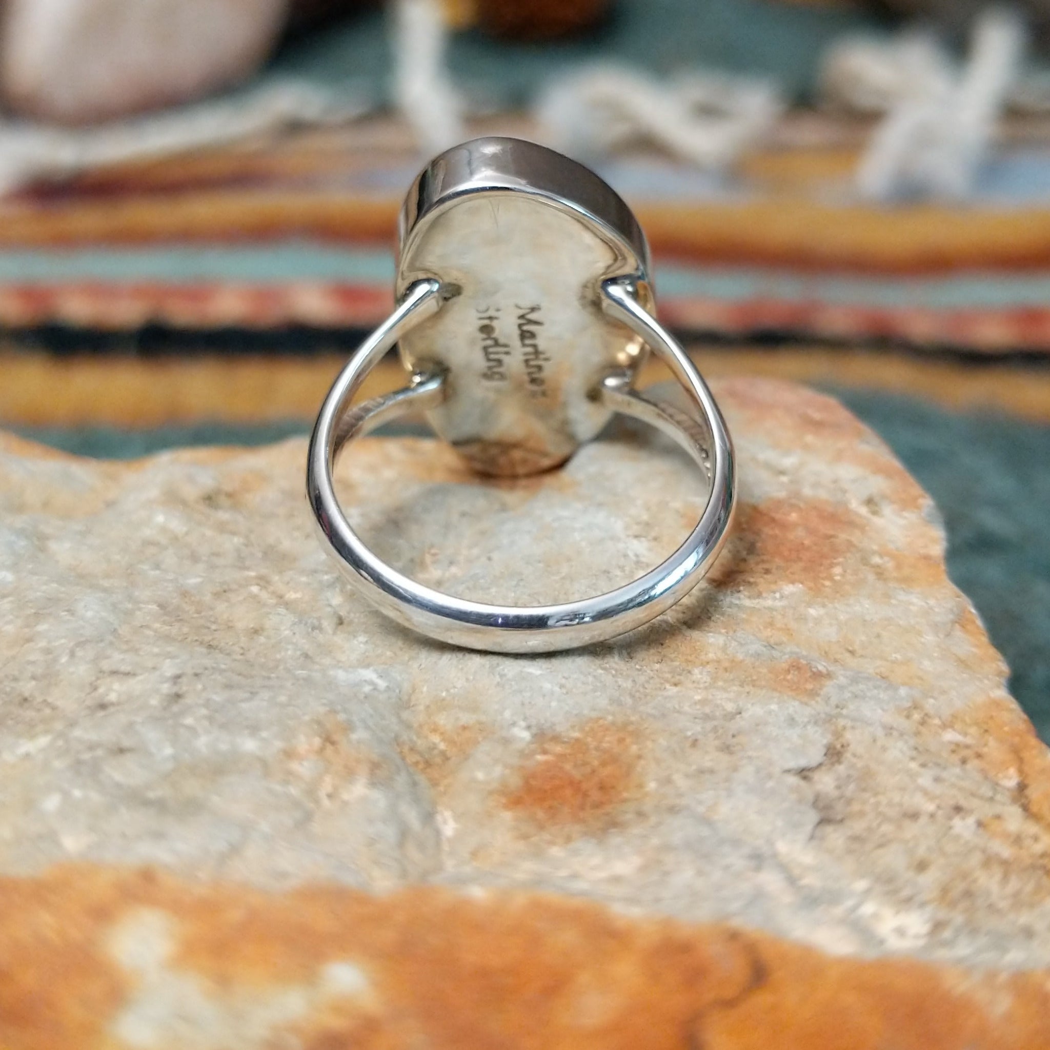 Sterling silver ring by Sheryl Martinez featuring an elongated oval White Buffalo stone with subtle dark veining and an elegant split-shank band; underside view.