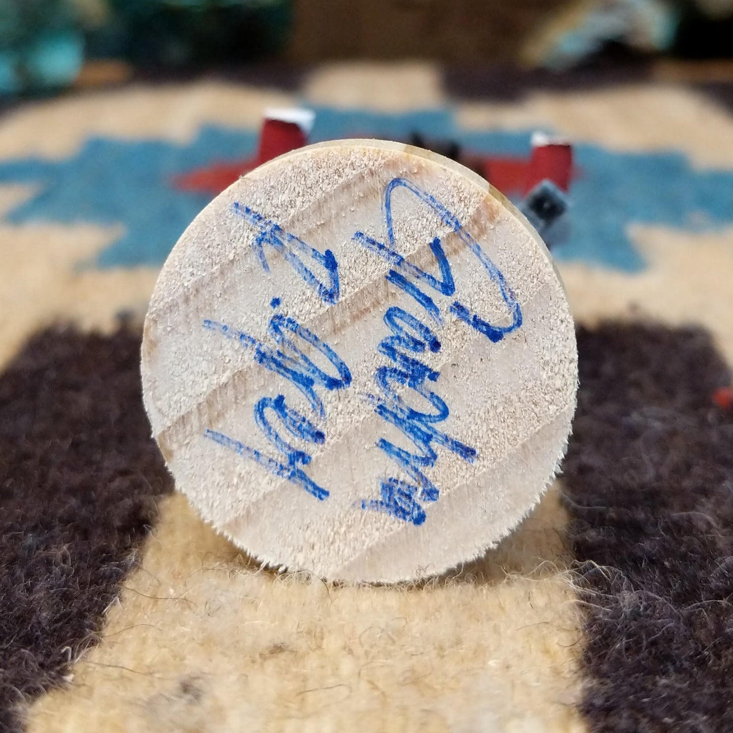 Underside of Grandmother mini kachina doll showing handwritten signature and label on wood base.