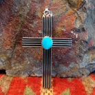 Grooved sterling silver cross pendant with single turquoise stone by Navajo artisan Francis Jones.