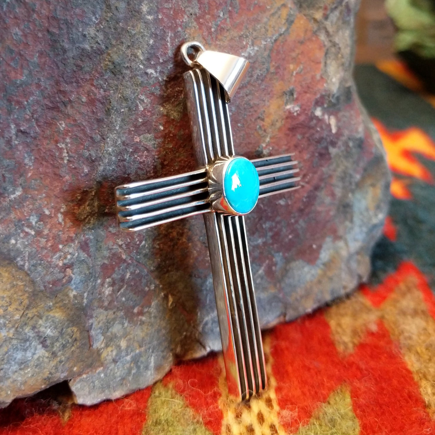 Grooved sterling silver cross pendant with single turquoise stone by Navajo artisan Francis Jones.