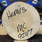 Underside of M. C. hemis kachina doll showing handwritten signature and label on wood base.