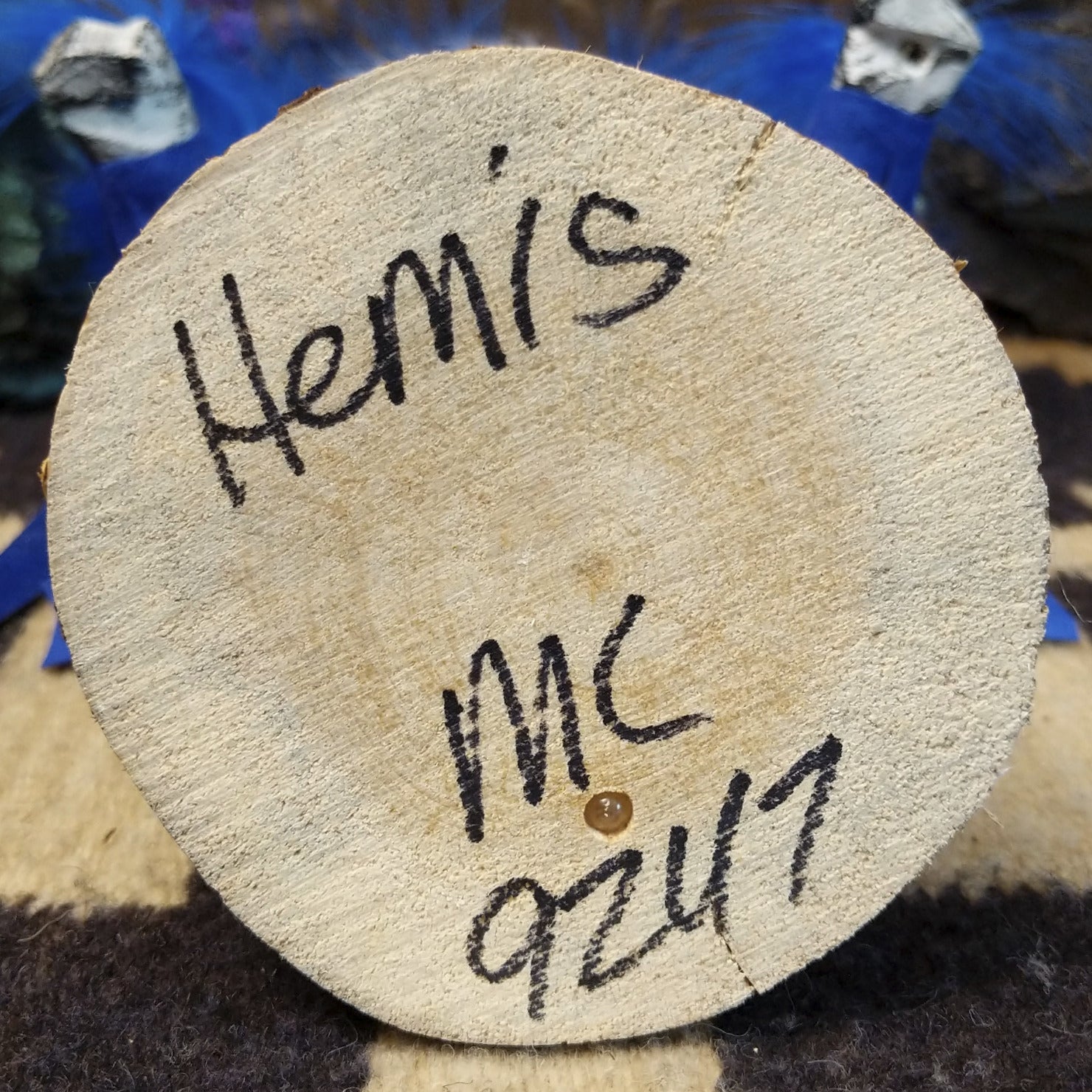 Underside of M. C. hemis kachina doll showing handwritten signature and label on wood base.