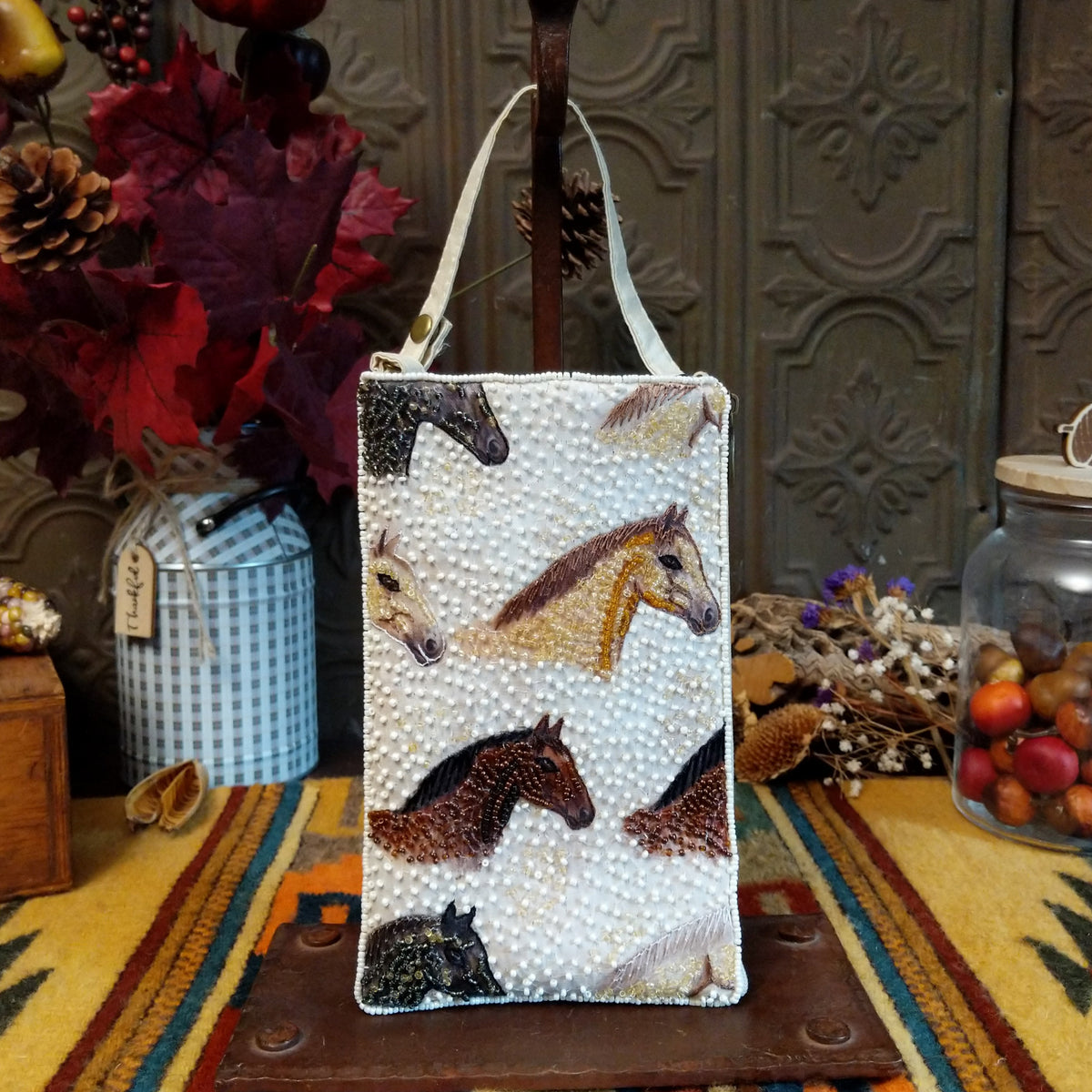 Herd Club Bag by Bamboo Trading featuring embroidered and beaded horse portraits in brown, black, cream, and golden tan on a shimmering white beaded background with a coordinating ivory shoulder strap.