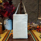 Herd Club Bag by Bamboo Trading featuring embroidered and beaded horse portraits in brown, black, cream, and golden tan on a shimmering white beaded background with a coordinating ivory shoulder strap; back side view.