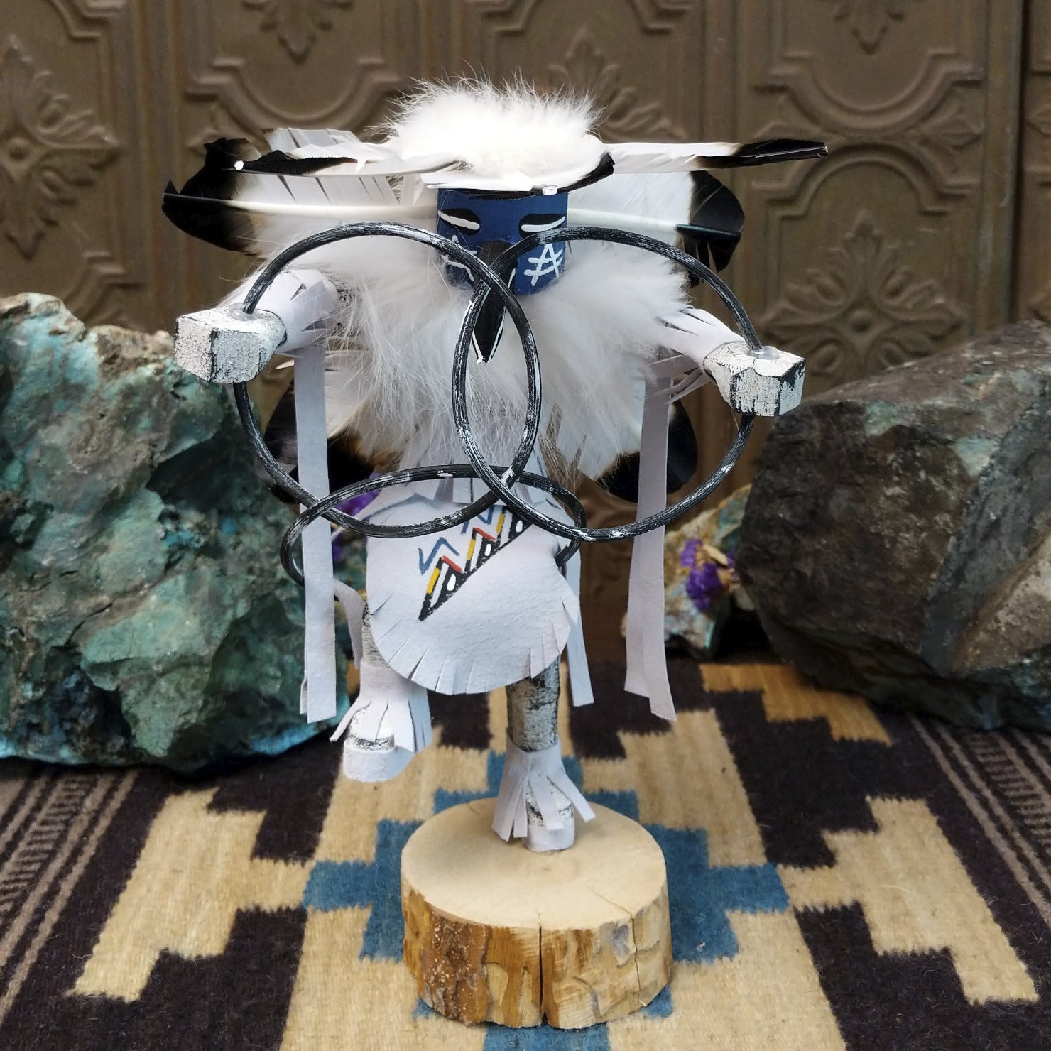 Navajo-made hoop dancer kachina doll by M. C. with blue mask, white feathers, and interwoven black hoops.
