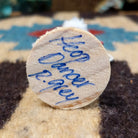 Underside of mini hoop dancer kachina doll showing handwritten signature and label on wood base.