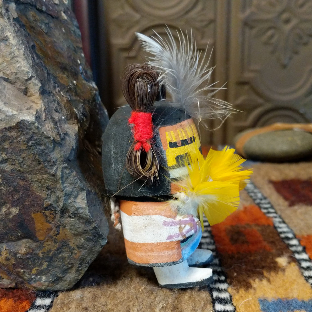 Wood carved into a corn maiden kachina with colorful paints, feathers, and horsehair.