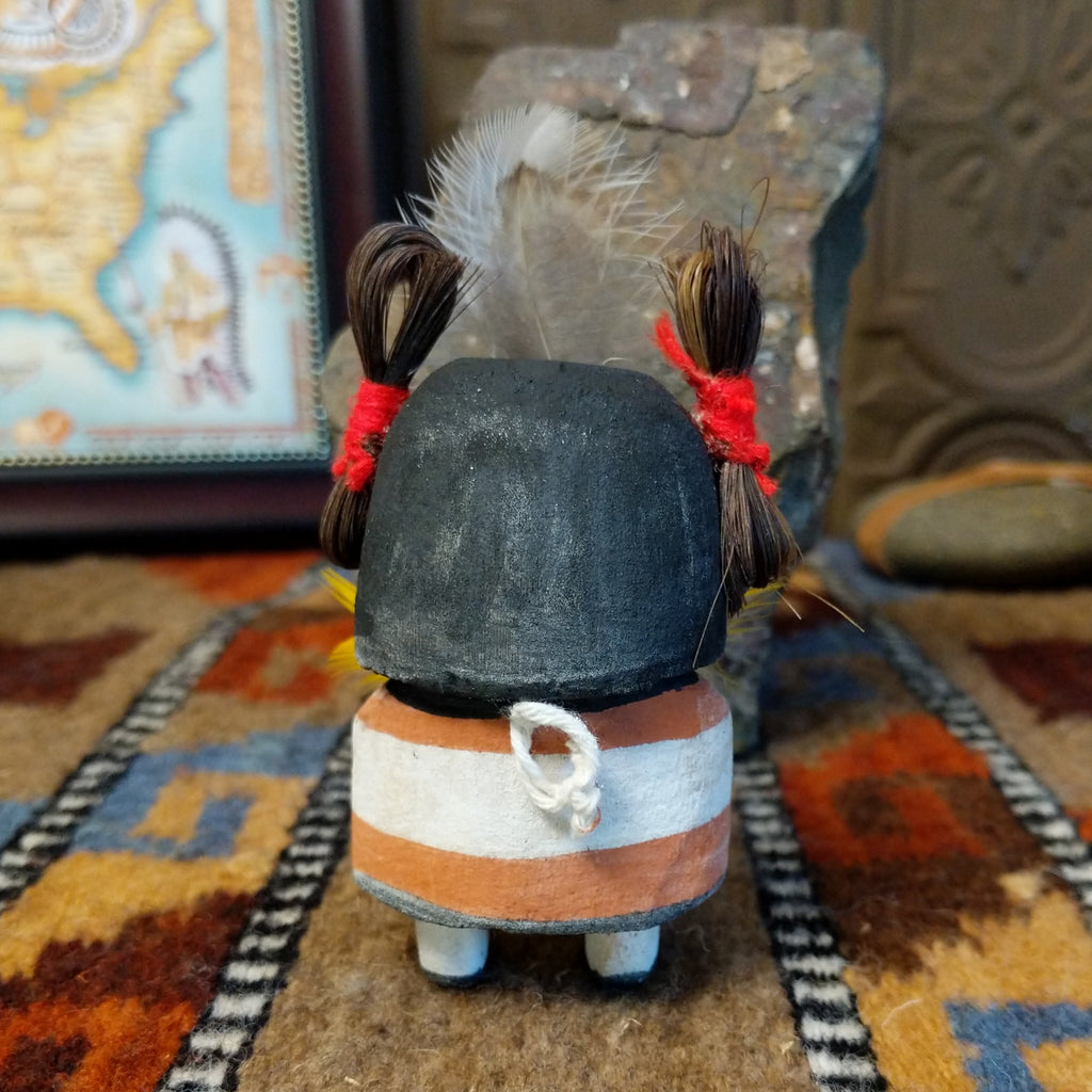 Wood carved into a corn maiden kachina with colorful paints, feathers, and horsehair.