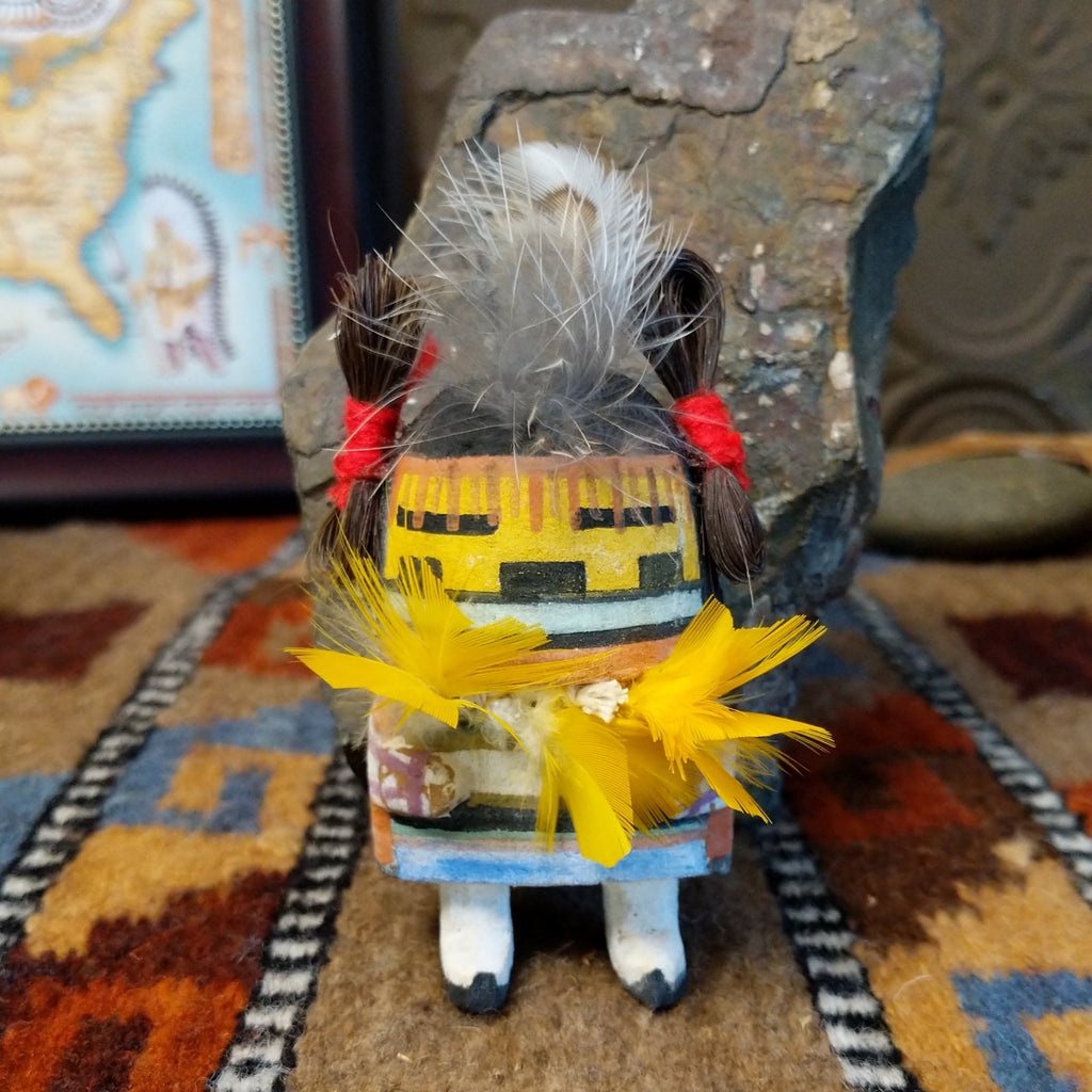 Wood carved into a corn maiden kachina with colorful paints, feathers, and horsehair.
