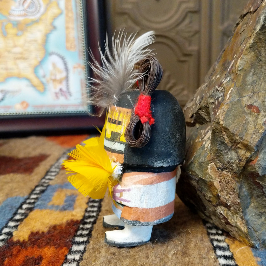 Wood carved into a corn maiden kachina with colorful paints, feathers, and horsehair.