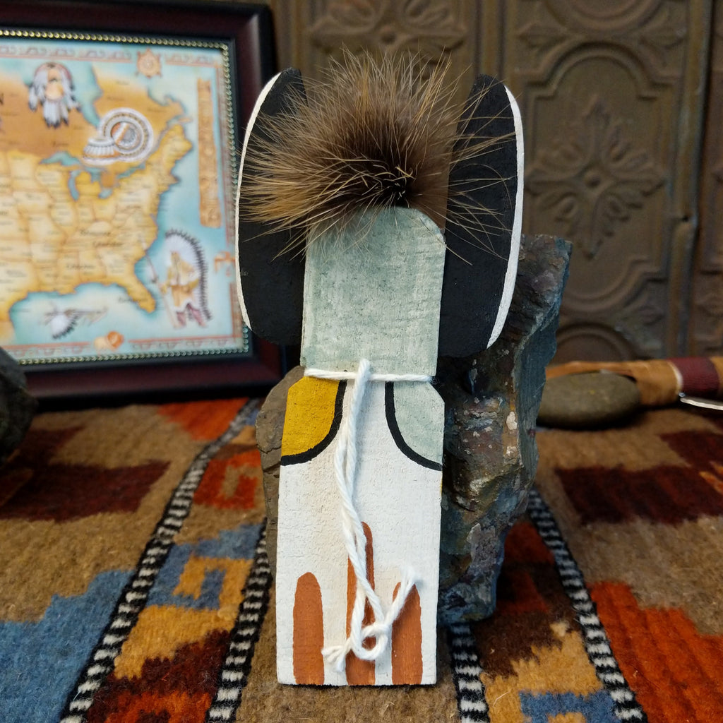 Wood carved into a crow mother kachina featuring tradition style of black and white paints with pop of colors and a feather at the top of the head.
