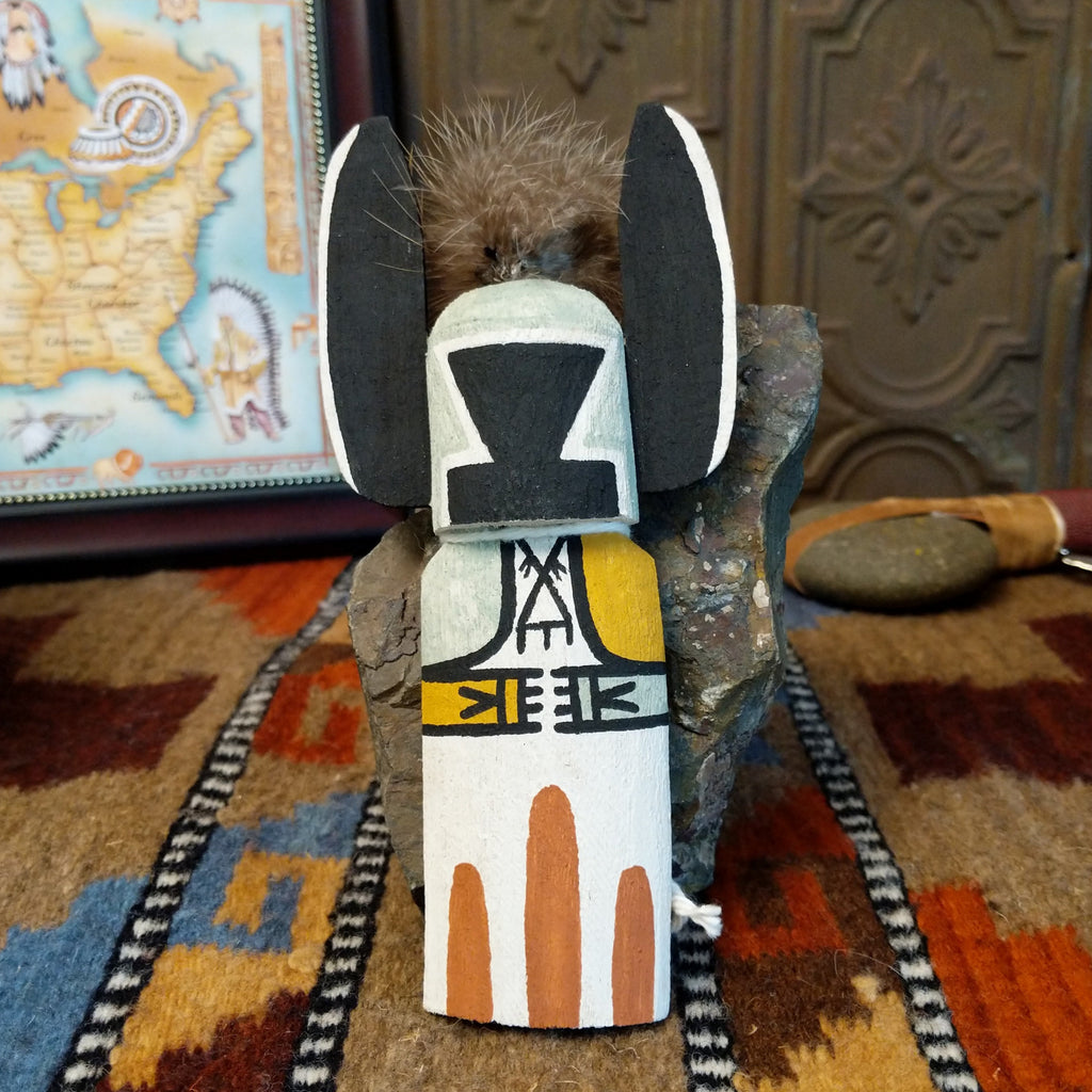 Wood carved into a crow mother kachina featuring tradition style of black and white paints with pop of colors and a feather at the top of the head.