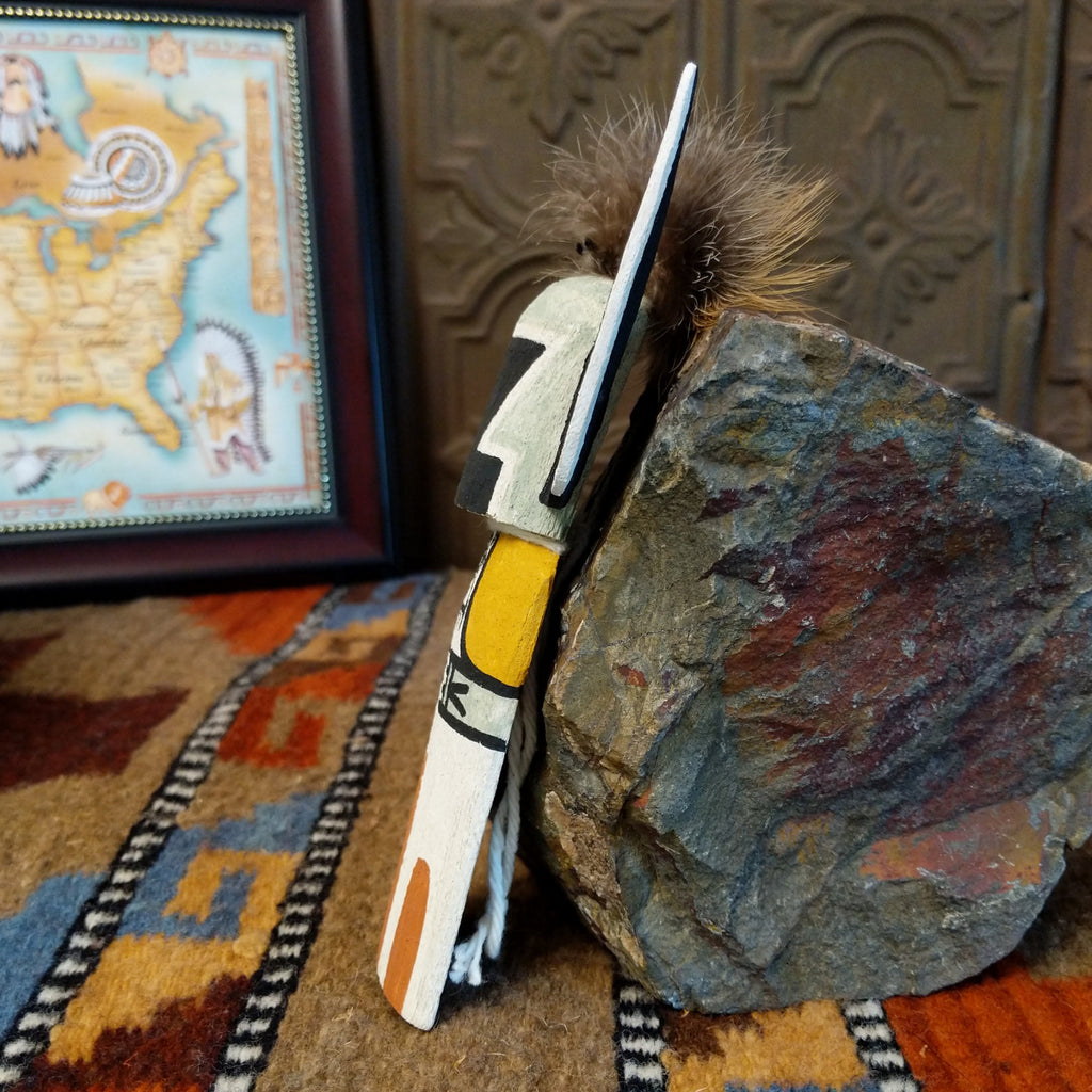 Wood carved into a crow mother kachina featuring tradition style of black and white paints with pop of colors and a feather at the top of the head.