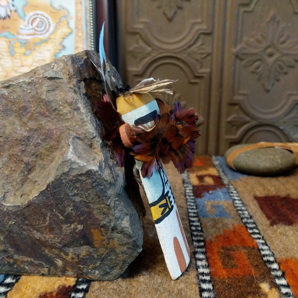 Wood carved into an eagle kachina with white, black, and colorful paint designs along the body and feathers on the chest and head.