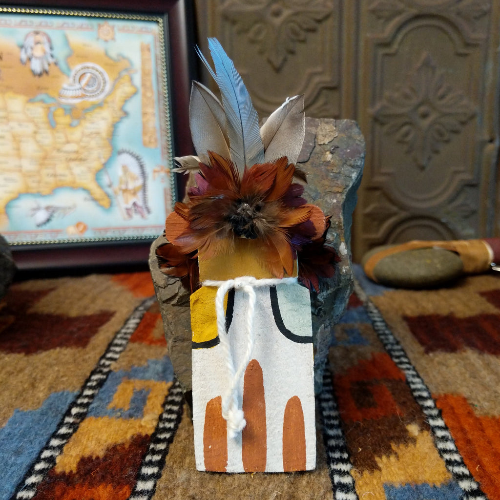 Wood carved into an eagle kachina with white, black, and colorful paint designs along the body and feathers on the chest and head.