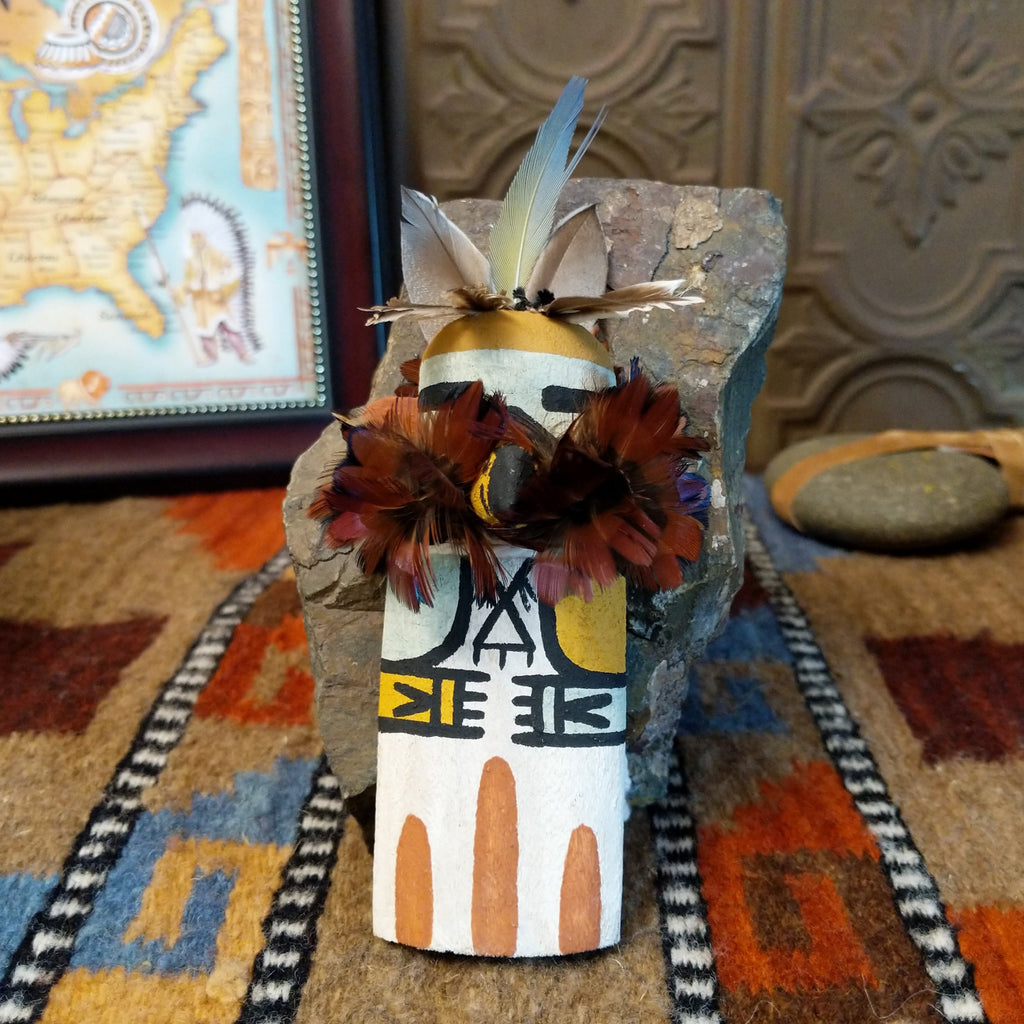 Wood carved into an eagle kachina with white, black, and colorful paint designs along the body and feathers on the chest and head.