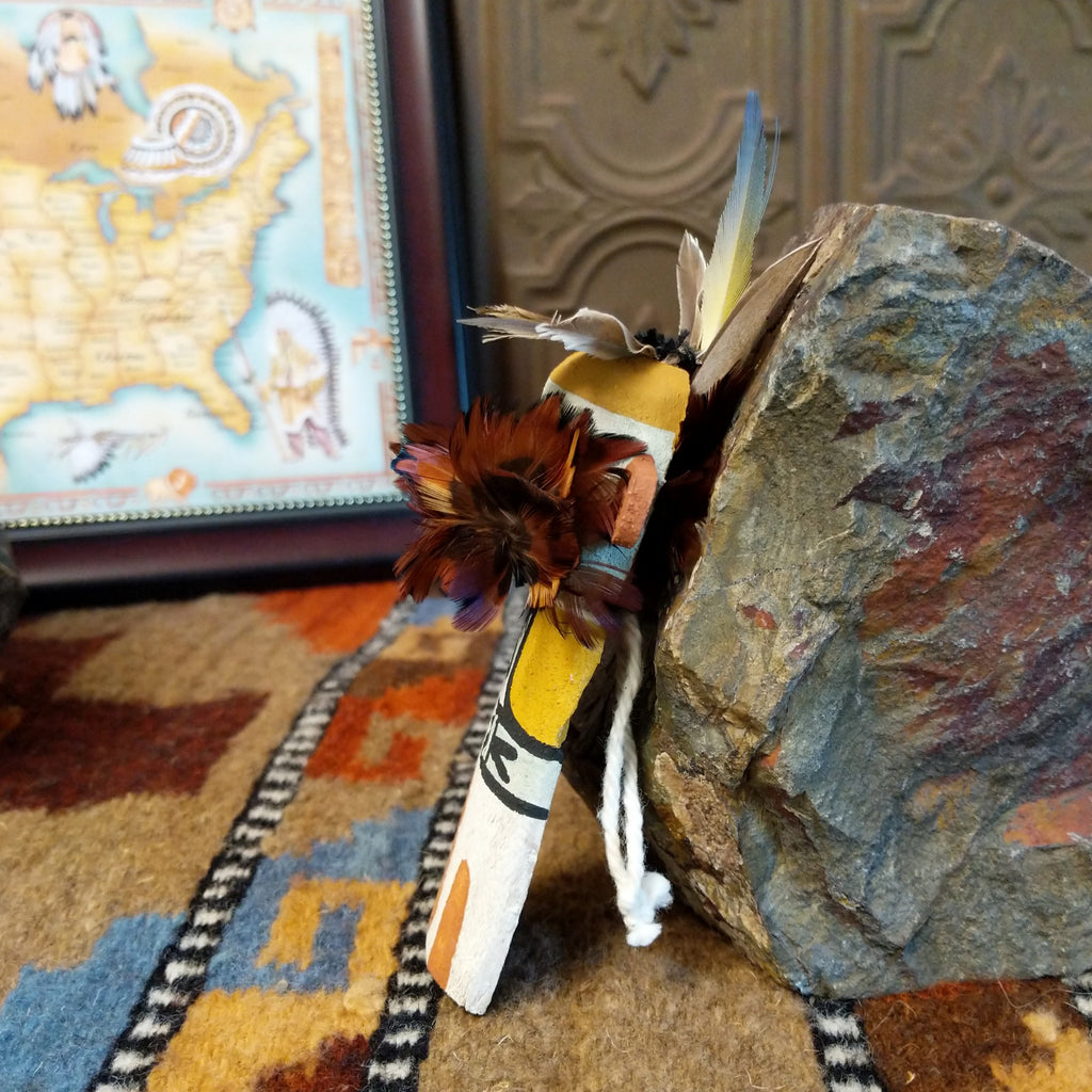 Wood carved into an eagle kachina with white, black, and colorful paint designs along the body and feathers on the chest and head.