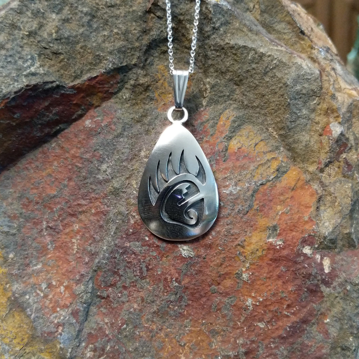 Hopi silver bear paw pendant by Loren Sakeva featuring a teardrop shape with polished silver and darkened recessed overlay-style detailing.