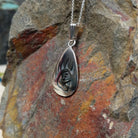 Hopi silver bear paw pendant by Loren Sakeva featuring a teardrop shape with polished silver and darkened recessed overlay-style detailing; side view.