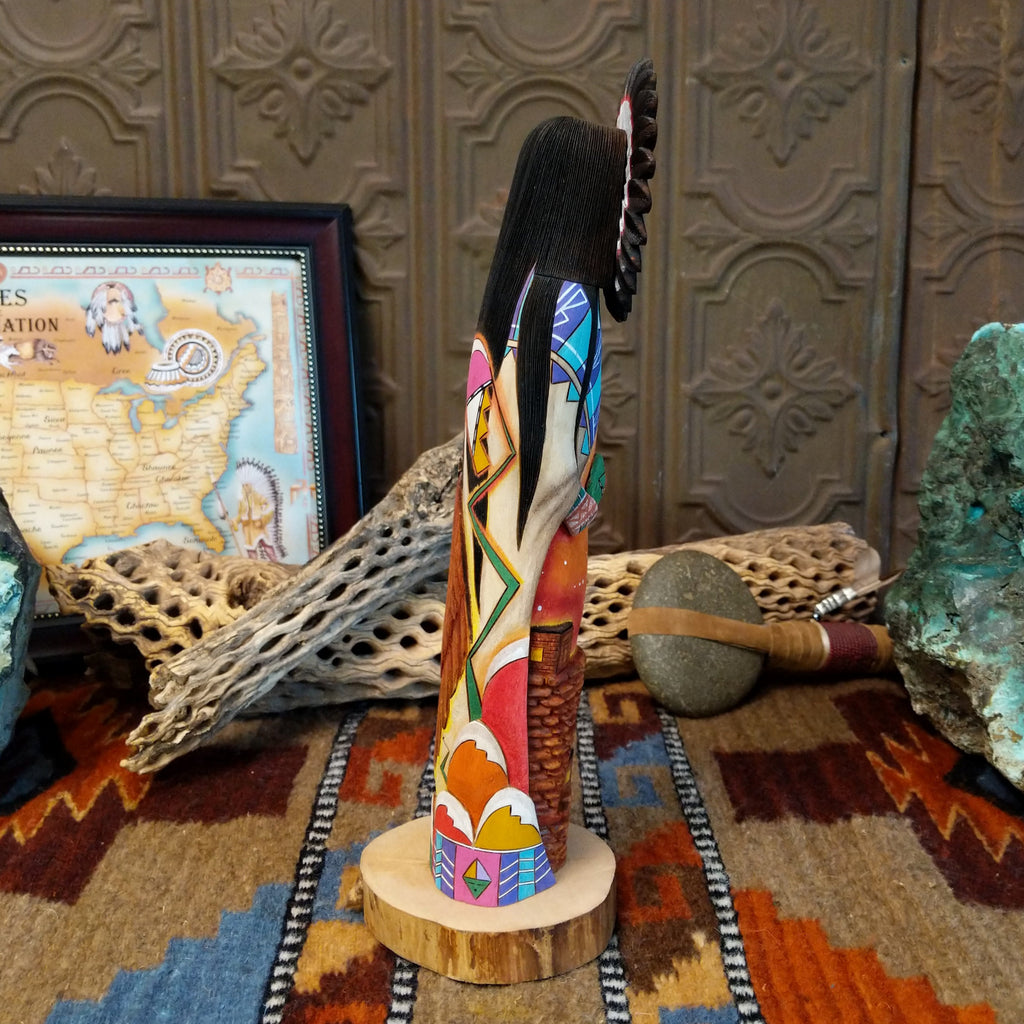 Wood carved into a sun kachina painted with vibrant colors and intricately carved wood details.