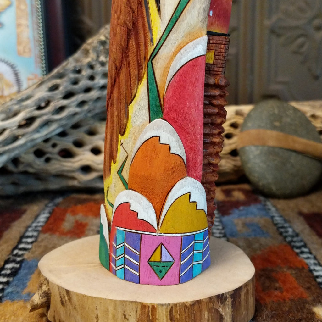 Wood carved into a sun kachina painted with vibrant colors and intricately carved wood details.