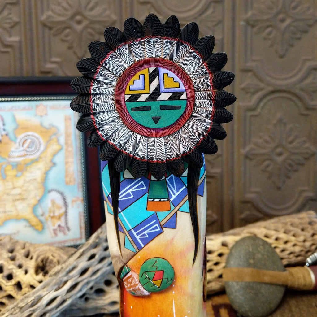 Wood carved into a sun kachina painted with vibrant colors and intricately carved wood details.