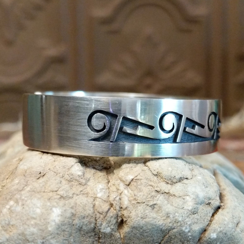 Sterling silver cuff with whirlwind and rain cloud motifs on the surface.