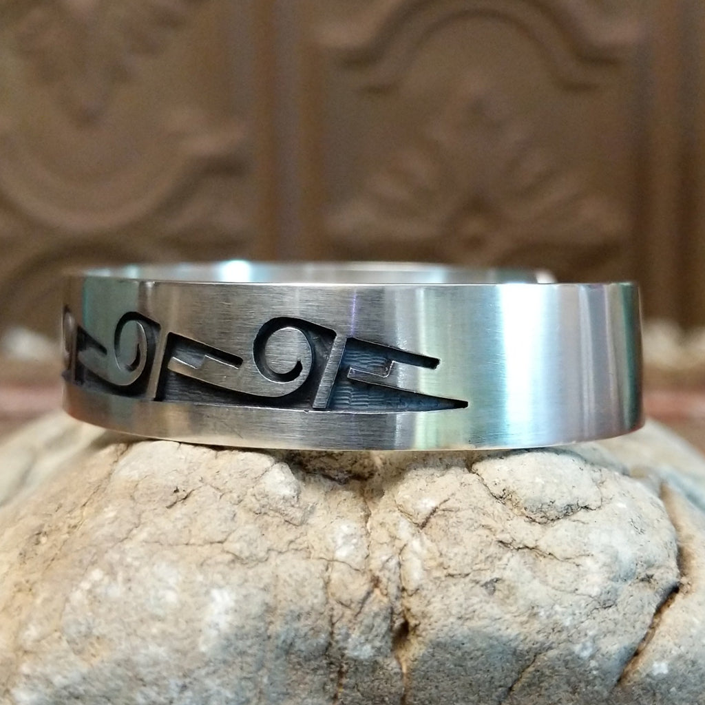 Sterling silver cuff with whirlwind and rain cloud motifs on the surface.
