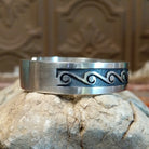 Sterling silver cuff with whirlwind motifs stamped on the surface.