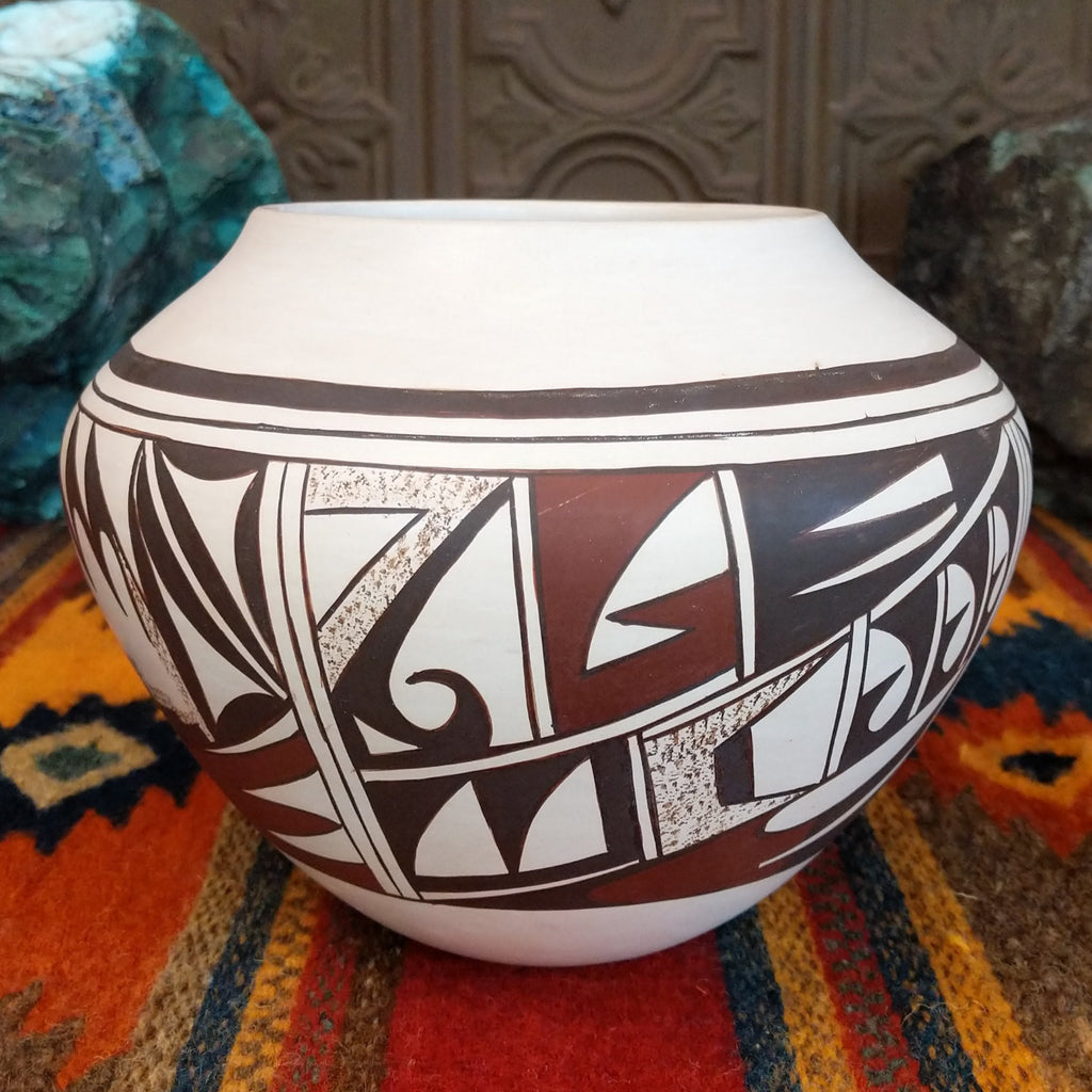 White clay with various geometric designs in brown and red with sponge techniques.