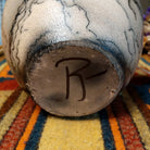 This distinctive Horsehair Pottery by Roger Calhoun features a rounded ceramic vessel with natural earth tones, delicate black horsehair patterns, a decorative crackled upper section, and a wide black rim; underside view with artist signature.