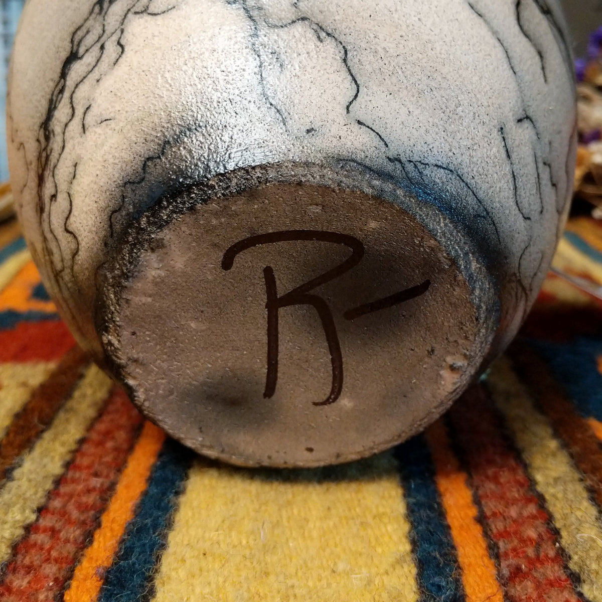This distinctive Horsehair Pottery by Roger Calhoun features a rounded ceramic vessel with natural earth tones, delicate black horsehair patterns, a decorative crackled upper section, and a wide black rim; underside view with artist signature.