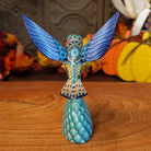 Polymer clay used to create a removable hummingbird and cactus, both painted vibrantly with floral motifs.
