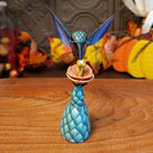 Polymer clay used to create a removable hummingbird and cactus, both painted vibrantly with floral motifs.