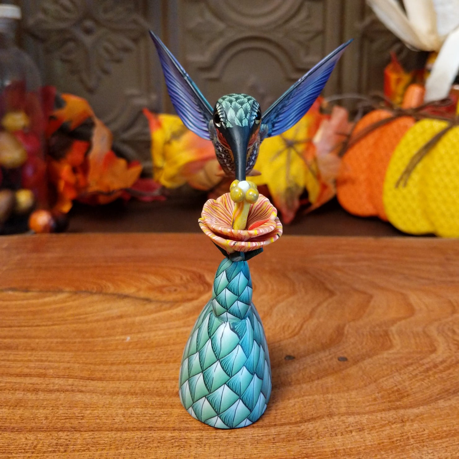 Polymer clay used to create a removable hummingbird and cactus, both painted vibrantly with floral motifs.