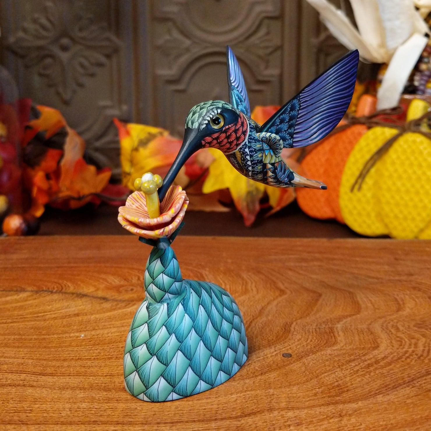 Polymer clay used to create a removable hummingbird and cactus, both painted vibrantly with floral motifs.