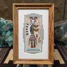 Framed Navajo sand painting of a Hunchback Yei figure with feather details and ceremonial elements. 