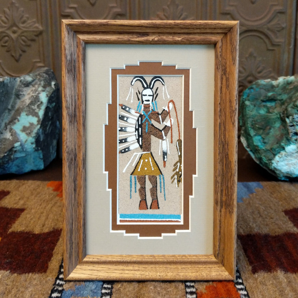 Colorful sand used to create a picture of a hunter set within a wooden frame.