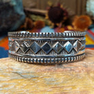 Wide silver cuff by Elvira Bill with repeating zigzag design, stamped accents, and detailed borders.