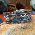 Wide silver cuff by Elvira Bill with repeating zigzag design, stamped accents, and detailed borders.